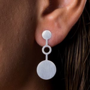 Detail of matt silver ondes earring placed on ear